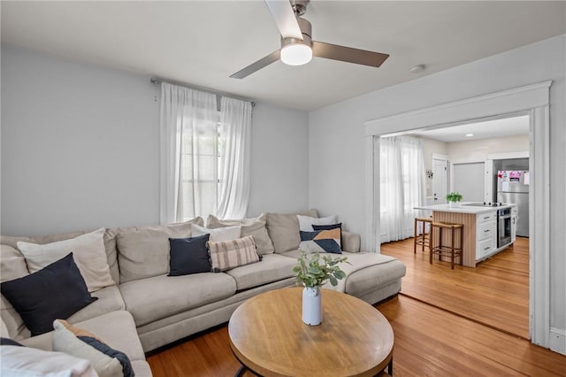 living room with light wood-type flooring and ceiling fan