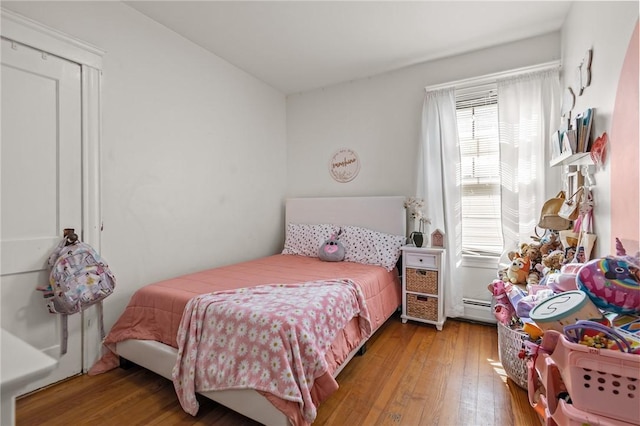 bedroom featuring multiple windows, wood finished floors, and a baseboard heating unit
