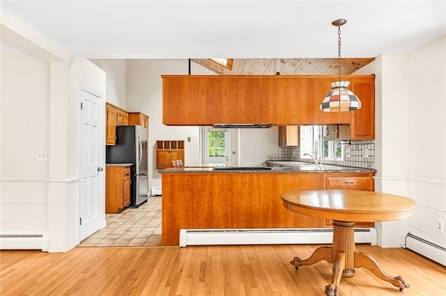 40 Wood Ave, Narragansett, RI 02882 - kitchen featuring freestanding refrigerator, brown cabinets, a peninsula, a baseboard radiator, and light wood-type flooring