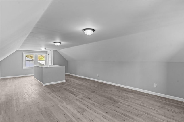 additional living space with wood finished floors, lofted ceiling, and baseboards