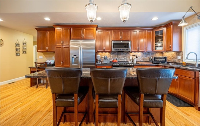 500 Mendon Rd Unit 116, Cumberland, RI 02864 - kitchen featuring appliances with stainless steel finishes, decorative backsplash, light wood-style flooring, a kitchen bar, and recessed lighting