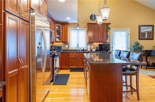 500 Mendon Rd Unit 116, Cumberland, RI 02864 - kitchen featuring stainless steel appliances, a kitchen breakfast bar, light wood-style flooring, decorative backsplash, and a center island