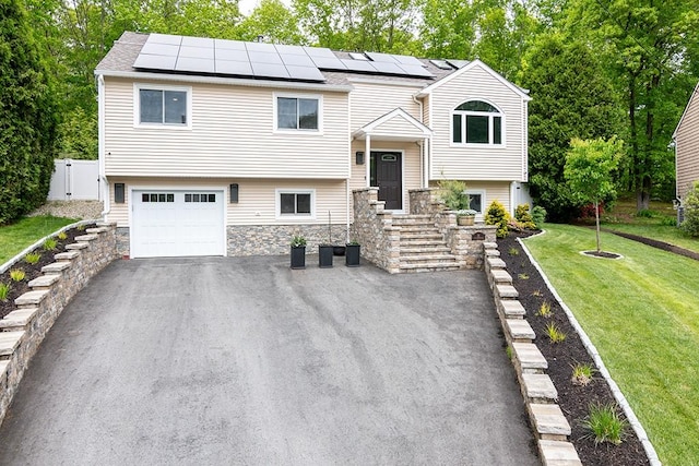 26 Ivy Hollow Ct, Cranston, RI 02921 - raised ranch with stone siding, roof mounted solar panels, an attached garage, and asphalt driveway