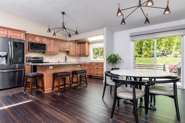 26 Ivy Hollow Ct, Cranston, RI 02921 - kitchen with stainless steel appliances, a kitchen island, tasteful backsplash, dark wood-style flooring, and a kitchen bar