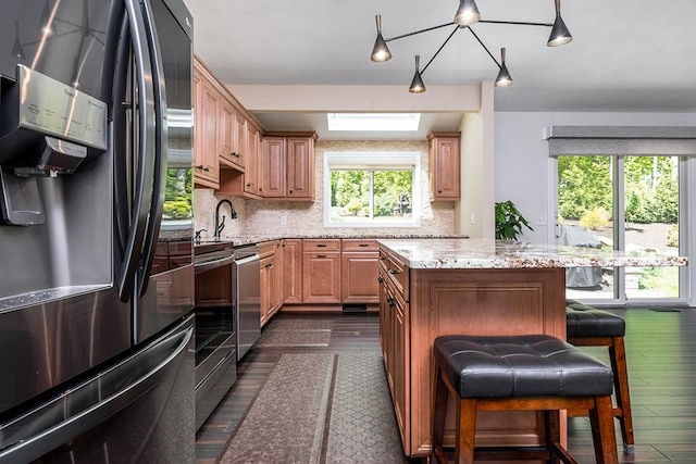 26 Ivy Hollow Ct, Cranston, RI 02921 - kitchen featuring stainless steel appliances, dark wood-style floors, light stone counters, a center island, and a breakfast bar area