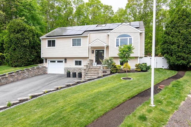 26 Ivy Hollow Ct, Cranston, RI 02921 - split foyer home with solar panels, an attached garage, asphalt driveway, stone siding, and a gate