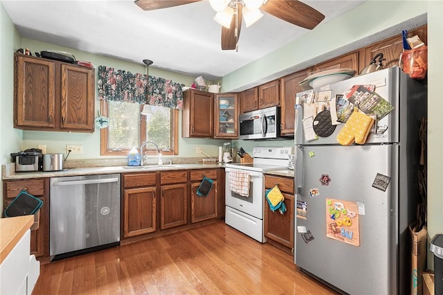 607 Brookhaven Ln, Woonsocket, RI 02895 - kitchen with appliances with stainless steel finishes, a sink, brown cabinetry, light wood-style flooring, and light countertops