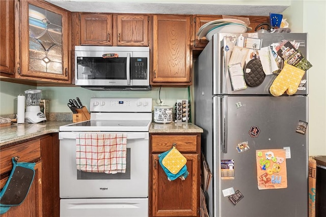 607 Brookhaven Ln, Woonsocket, RI 02895 - kitchen featuring appliances with stainless steel finishes, brown cabinets, glass insert cabinets, and light countertops