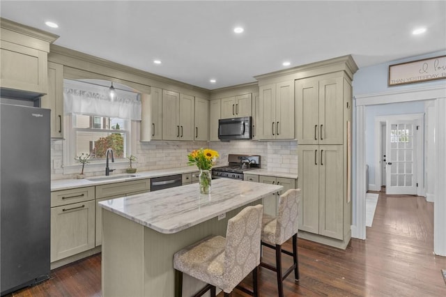 261 Columbus Ave, Pawtucket, RI 02861 - kitchen featuring stainless steel appliances, a sink, backsplash, a breakfast bar, and dark wood-type flooring