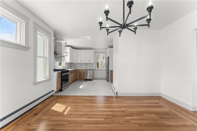 1314 Chalkstone Ave, Providence, RI 02908 - kitchen with stainless steel appliances, a baseboard heating unit, a chandelier, and wall chimney range hood