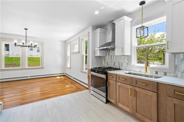 1314 Chalkstone Ave, Providence, RI 02908 - kitchen featuring a chandelier, stainless steel gas range oven, wall chimney exhaust hood, a sink, and a baseboard radiator