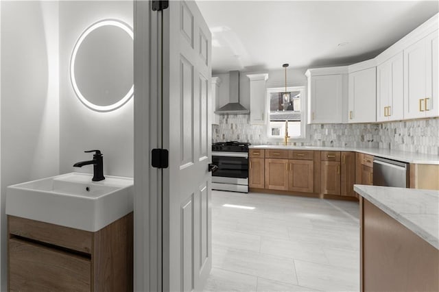 1314 Chalkstone Ave, Providence, RI 02908 - kitchen with appliances with stainless steel finishes, wall chimney range hood, backsplash, decorative light fixtures, and white cabinetry