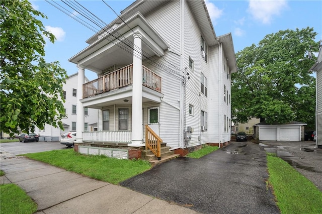 view of front of property with a balcony, an outbuilding, and a garage