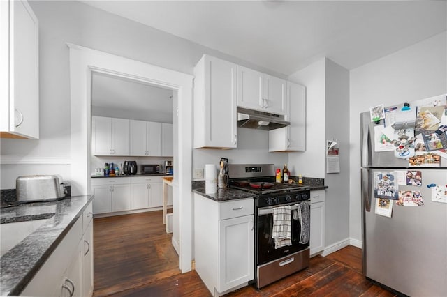 kitchen with appliances with stainless steel finishes, under cabinet range hood, dark wood-style floors, dark stone counters, and white cabinets