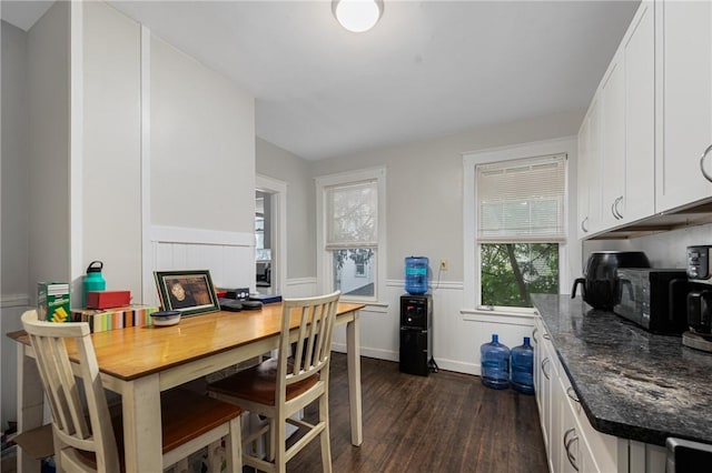 dining area with dark wood-style flooring and a wainscoted wall