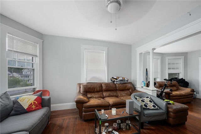 living area featuring ornate columns, ceiling fan, wood finished floors, and baseboards