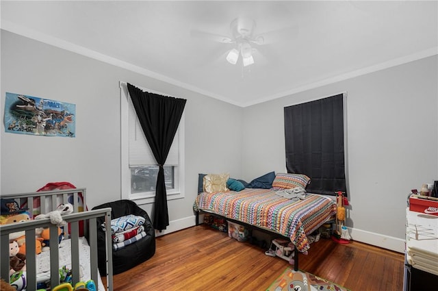 bedroom with baseboards, hardwood / wood-style floors, crown molding, and a ceiling fan