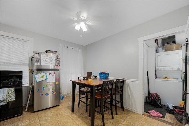 dining space featuring stacked washing machine and dryer, a ceiling fan, wainscoting, and tile patterned floors
