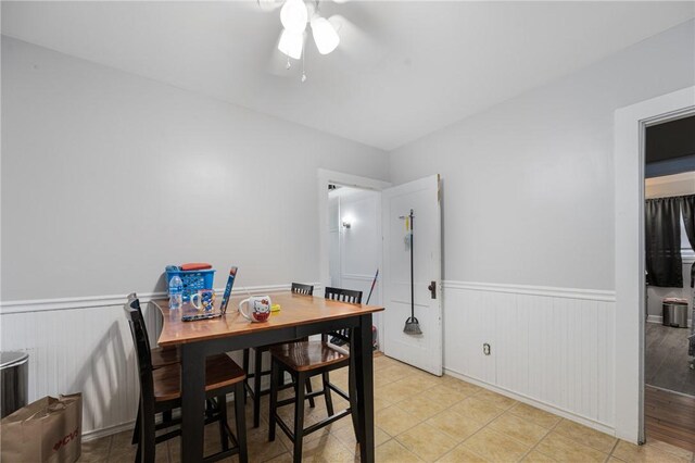 dining room featuring wainscoting, ceiling fan, and light tile patterned flooring