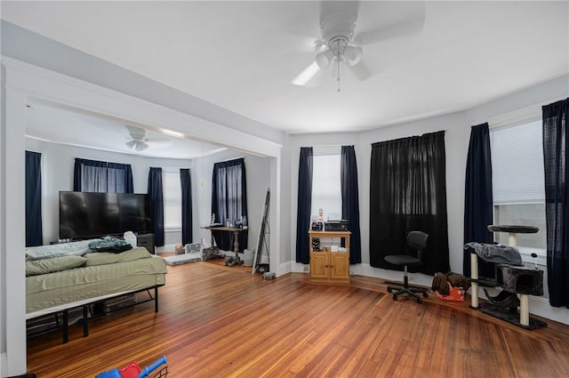 living area with a ceiling fan, light wood-style floors, and baseboards