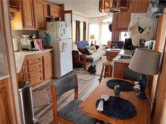 118 Dunns Corner Rd, Westerly, RI 02891 - kitchen with freestanding refrigerator, wood finished floors, light countertops, brown cabinetry, and open floor plan