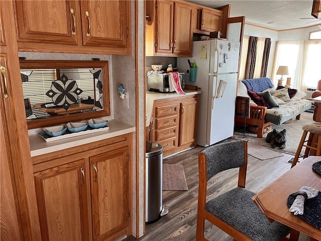118 Dunns Corner Rd, Westerly, RI 02891 - kitchen featuring freestanding refrigerator, brown cabinets, light countertops, dark wood-type flooring, and crown molding