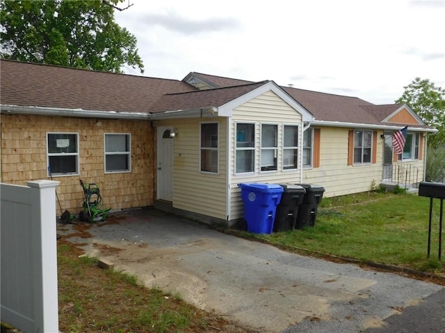 view of front of house with roof with shingles and a front yard