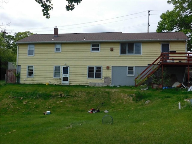 back of property with stairway, a deck, a chimney, and a lawn