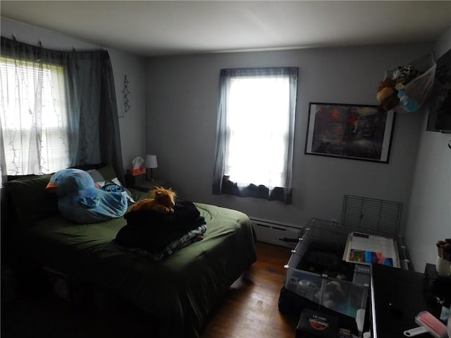 bedroom featuring a baseboard heating unit and wood finished floors