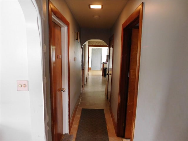corridor with arched walkways and baseboards