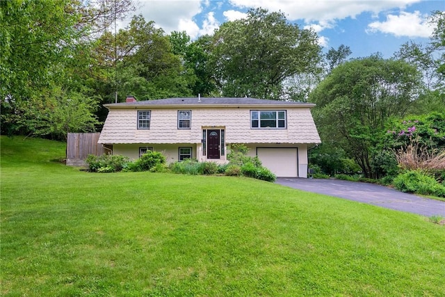 40 Haverhill Ave, North Kingstown, RI 02852 - bi-level home featuring asphalt driveway, a garage, a front yard, a chimney, and view of wooded area