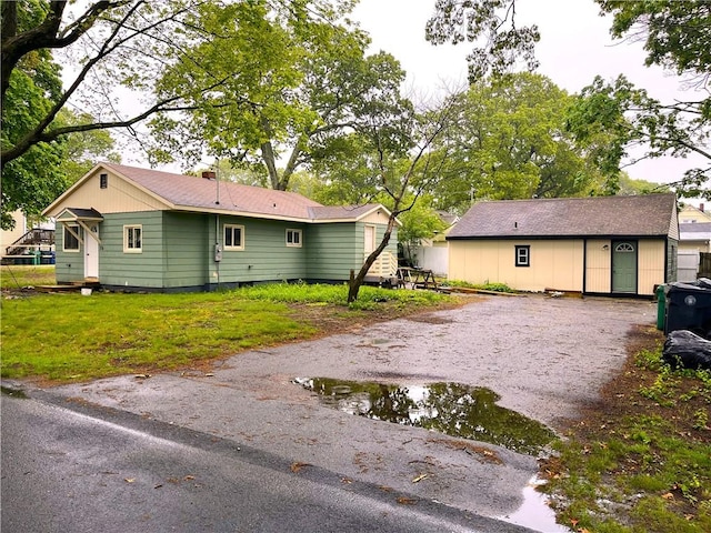 view of side of home with dirt driveway and a yard