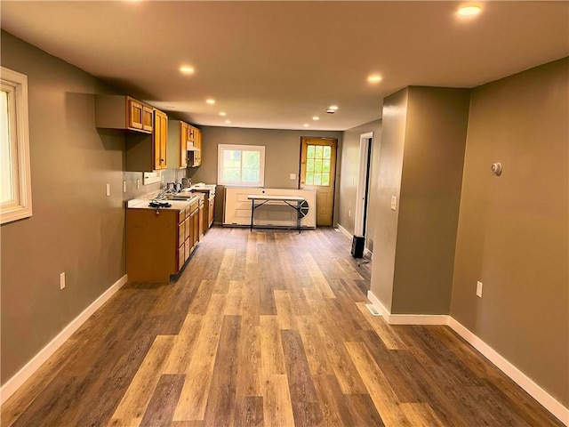 kitchen featuring wood finished floors, recessed lighting, a sink, baseboards, and light countertops