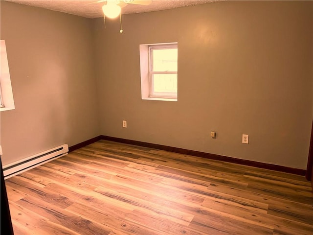 unfurnished room with a baseboard heating unit, wood finished floors, ceiling fan, baseboards, and a textured ceiling
