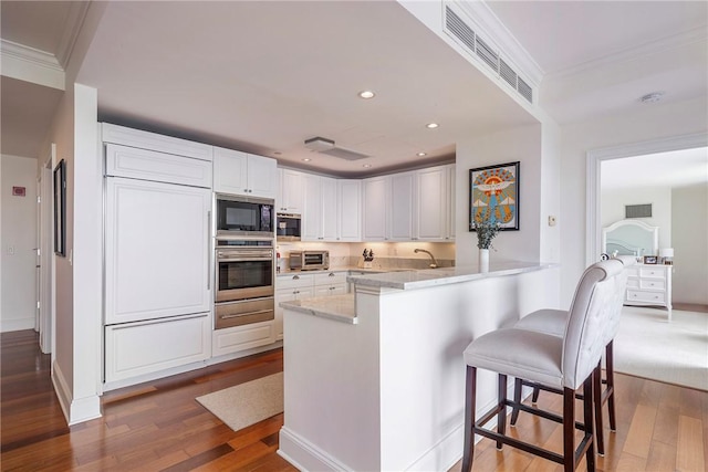 1 Tower Dr Unit 203, Portsmouth, RI 02871 - kitchen featuring oven, black microwave, a peninsula, a warming drawer, and dark wood-style flooring