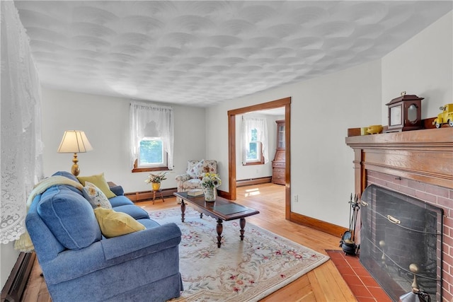 72 Old Danielson Pike, Foster, RI 02825 - living area featuring a baseboard heating unit, light wood-type flooring, baseboard heating, a fireplace, and baseboards
