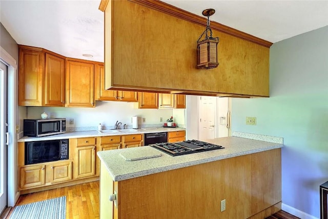 9 Misty River Ter, Narragansett, RI 02874 - kitchen with black appliances, a peninsula, light countertops, light wood-style flooring, and a sink
