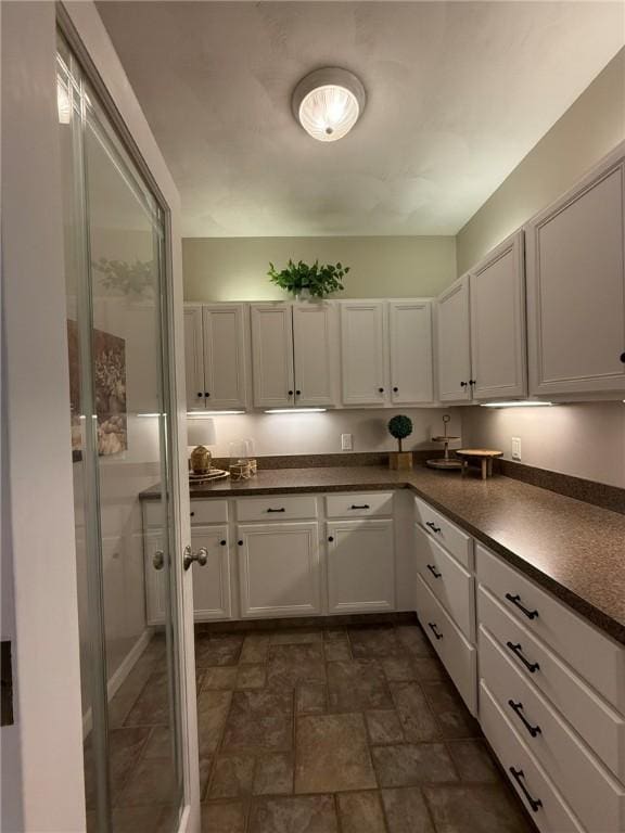 36 Jasmine Cir, North Kingstown, RI 02874 - kitchen with dark countertops, stone finish flooring, and white cabinets