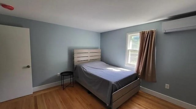 132 Maple Ave, Middletown, RI 02842 - bedroom featuring an AC wall unit, wood finished floors, and baseboards