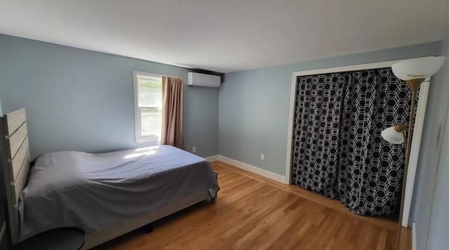 132 Maple Ave, Middletown, RI 02842 - bedroom with a wall unit AC, light wood-type flooring, and baseboards