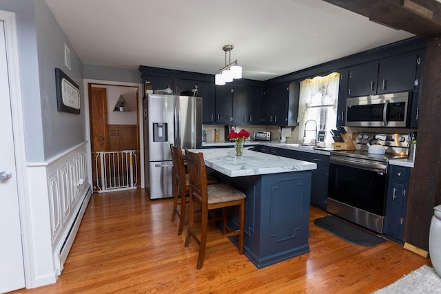 60 Sumach Ave, East Providence, RI 02915 - kitchen featuring stainless steel appliances, a baseboard heating unit, a center island, light wood-type flooring, and a wainscoted wall