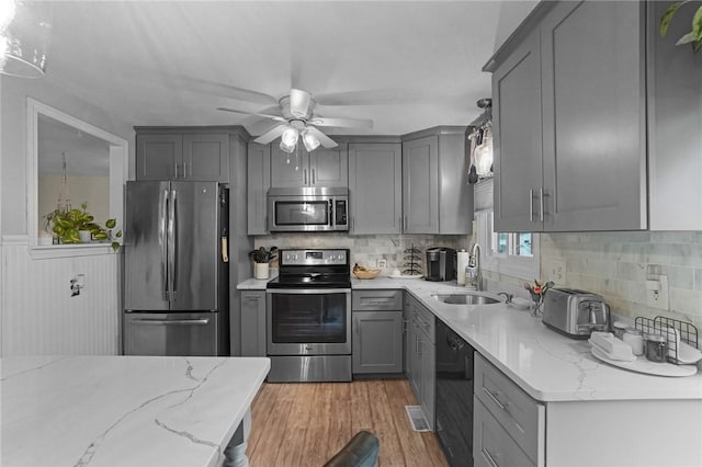 52 Eddy St, North Providence, RI 02911 - kitchen featuring appliances with stainless steel finishes, a sink, gray cabinetry, light wood finished floors, and light stone countertops