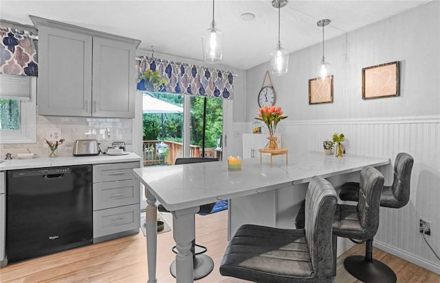 52 Eddy St, North Providence, RI 02911 - kitchen with dishwasher, gray cabinetry, light wood-type flooring, a breakfast bar, and a wainscoted wall