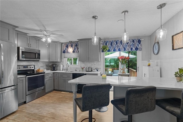 52 Eddy St, North Providence, RI 02911 - kitchen with stainless steel appliances, gray cabinetry, decorative backsplash, light stone counters, and ceiling fan