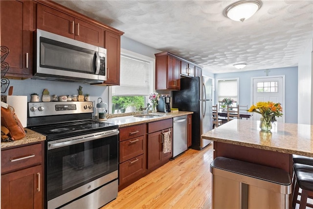 27 Aberdeen St, West Warwick, RI 02893 - kitchen with stainless steel appliances, plenty of natural light, light wood finished floors, a kitchen bar, and a textured ceiling