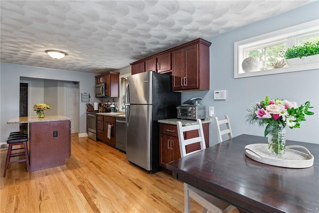 27 Aberdeen St, West Warwick, RI 02893 - kitchen featuring stainless steel appliances, light wood finished floors, a kitchen breakfast bar, a textured ceiling, and a center island