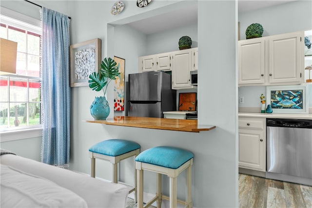 97 Narragansett Ave Unit C4, Newport, RI 02840 - kitchen with appliances with stainless steel finishes, white cabinetry, light wood-type flooring, and a breakfast bar area