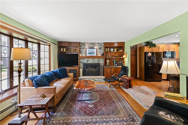 10 Bartlett Rd, Middletown, RI 02842 - living room featuring light wood-style flooring, a baseboard radiator, a stone fireplace, and built in shelves