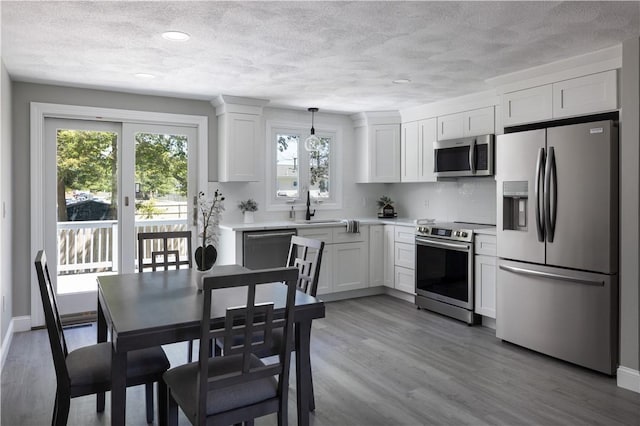 99 Scranton Ave, Warwick, RI 02888 - kitchen featuring appliances with stainless steel finishes, a textured ceiling, light countertops, white cabinetry, and light wood-type flooring