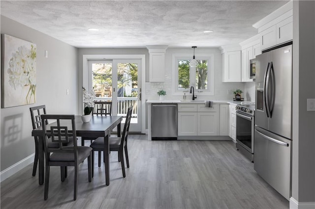 99 Scranton Ave, Warwick, RI 02888 - kitchen with stainless steel appliances, light countertops, white cabinets, light wood-style flooring, and a textured ceiling